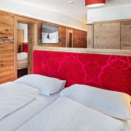 Alpine-style hotel room with wood interiors and a red headboard, exuding warmth and comfort.